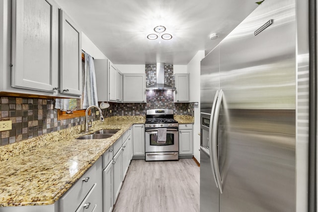 kitchen with wall chimney range hood, light hardwood / wood-style flooring, sink, gray cabinetry, and stainless steel appliances