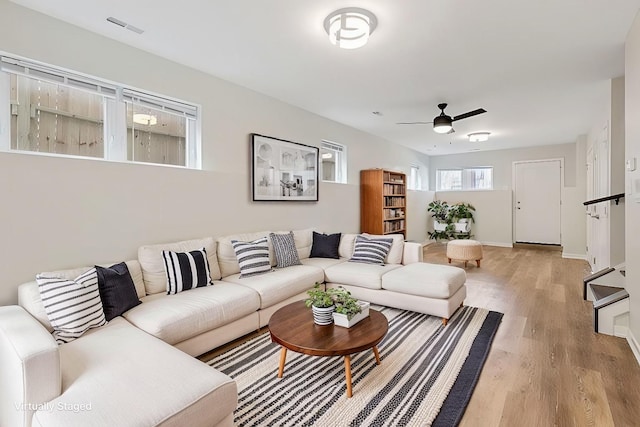 living area with baseboards, visible vents, light wood-type flooring, and ceiling fan