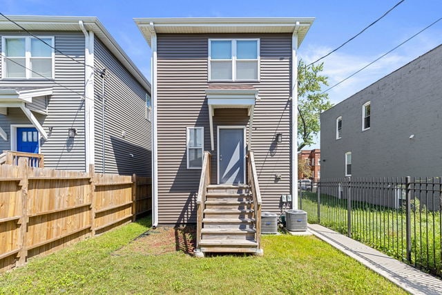 back of property featuring cooling unit and a lawn