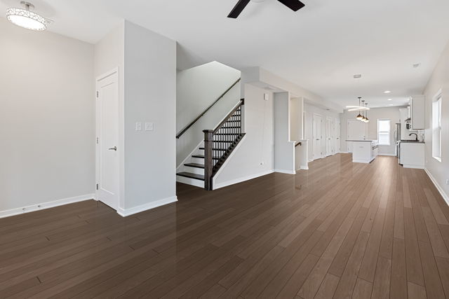 unfurnished living room featuring ceiling fan and dark wood-type flooring