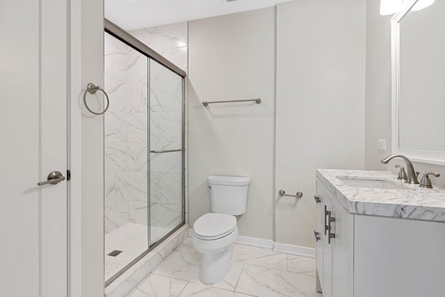 bathroom featuring vanity, a shower with door, and toilet