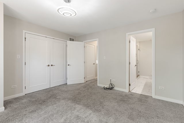 unfurnished bedroom with a closet, light colored carpet, and ensuite bathroom