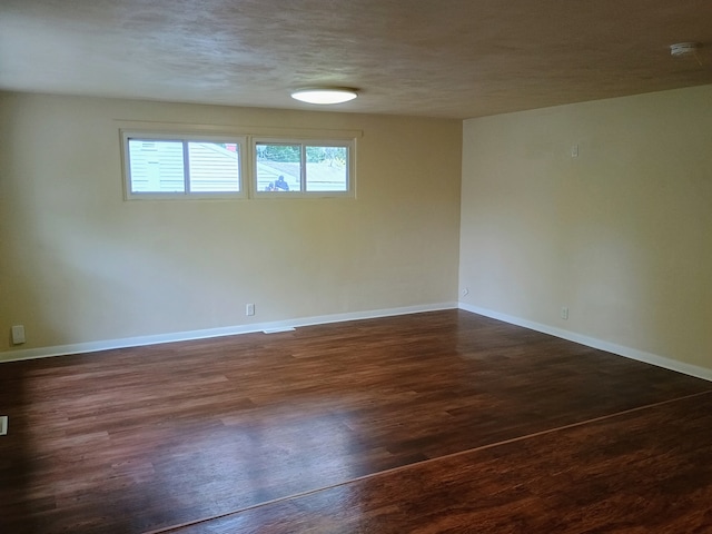 empty room with plenty of natural light, dark hardwood / wood-style floors, and a textured ceiling