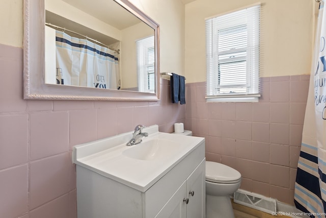 bathroom featuring walk in shower, toilet, vanity, and tile walls