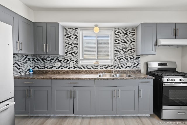 kitchen featuring white refrigerator, stainless steel gas range oven, light wood-type flooring, and sink