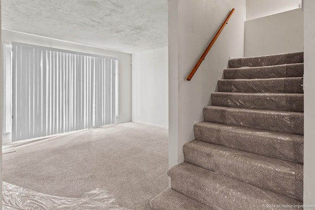 stairs featuring a textured ceiling