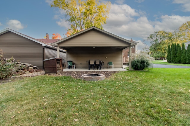 rear view of house with a fire pit, a lawn, and a patio