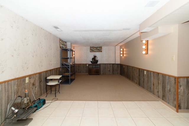 basement featuring wood walls and light carpet