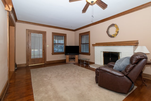 living room featuring ceiling fan, a fireplace, crown molding, and hardwood / wood-style floors