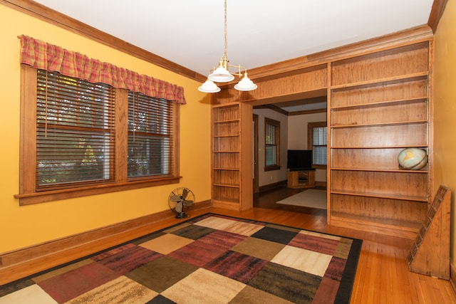 unfurnished room featuring ornamental molding, hardwood / wood-style floors, and a notable chandelier