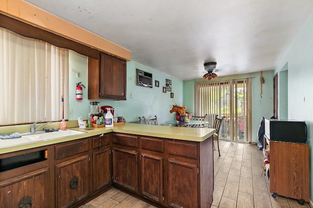 kitchen with kitchen peninsula, dark brown cabinetry, sink, and ceiling fan