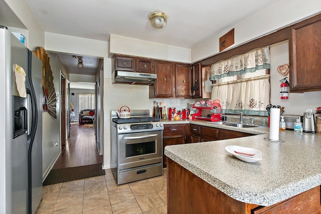 kitchen featuring light wood-type flooring, sink, kitchen peninsula, appliances with stainless steel finishes, and plenty of natural light