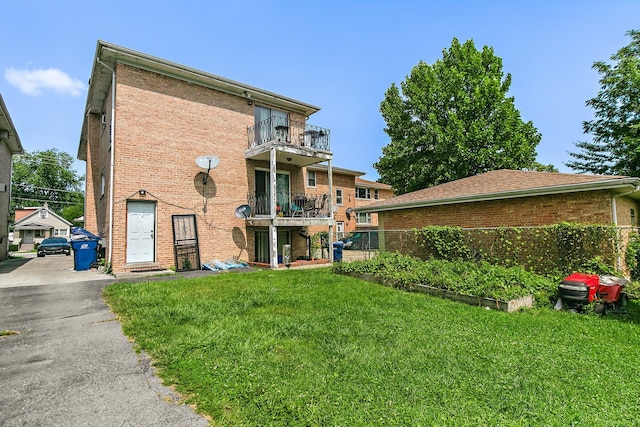 back of house with a balcony and a yard