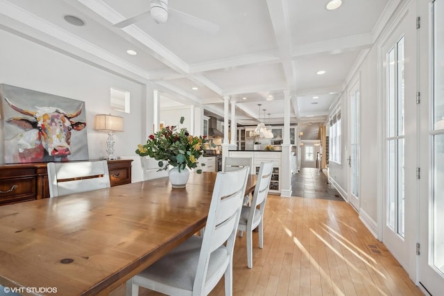 dining space featuring beamed ceiling, coffered ceiling, ceiling fan, crown molding, and light wood-type flooring