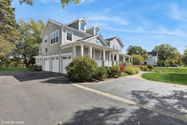 view of side of home with a garage, covered porch, and a lawn