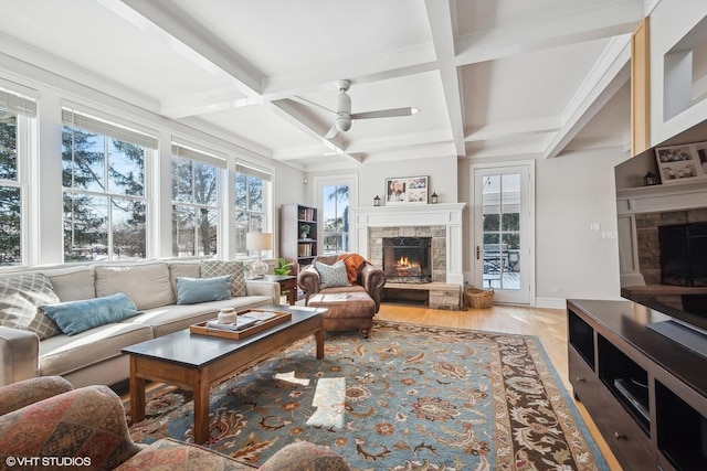 living room featuring a stone fireplace, coffered ceiling, beam ceiling, and light wood-type flooring