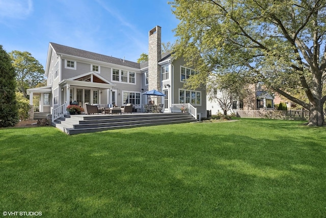 back of house with a deck and a lawn