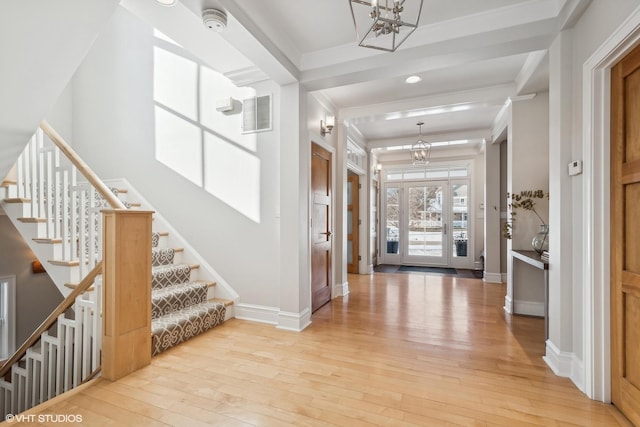 foyer entrance with ornamental molding, a chandelier, and light hardwood / wood-style flooring