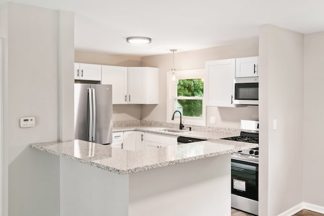 kitchen with sink, light stone counters, stainless steel appliances, kitchen peninsula, and white cabinetry