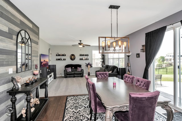 dining space with ceiling fan with notable chandelier and dark hardwood / wood-style flooring