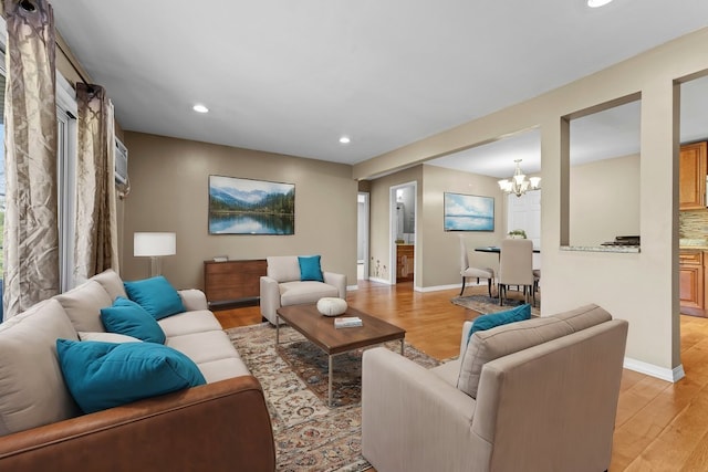 living room with an inviting chandelier, light hardwood / wood-style flooring, and a wall mounted air conditioner