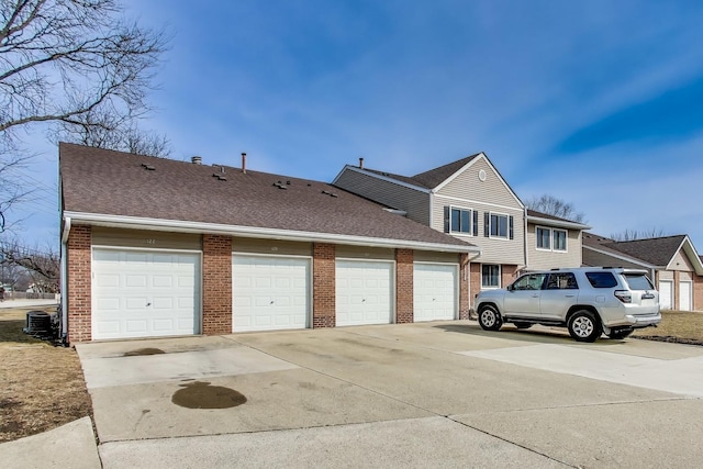 view of side of property with a garage, brick siding, and roof with shingles