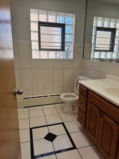 bathroom featuring toilet, tile patterned floors, tile walls, a baseboard heating unit, and vanity