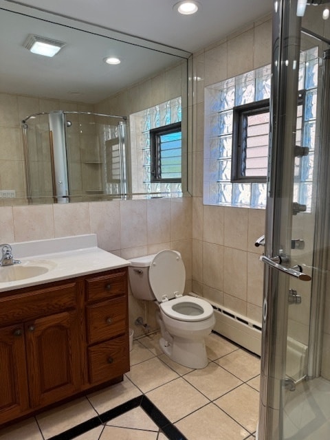 bathroom with an enclosed shower, toilet, tile walls, and vanity