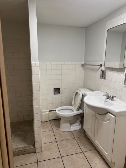 bathroom with tile walls, baseboard heating, vanity, and toilet