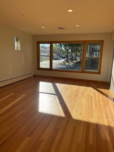 empty room featuring a baseboard radiator and hardwood / wood-style floors