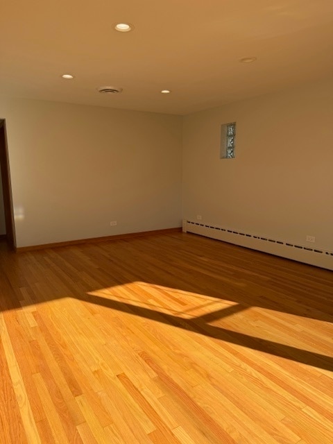 empty room with light hardwood / wood-style floors and baseboard heating