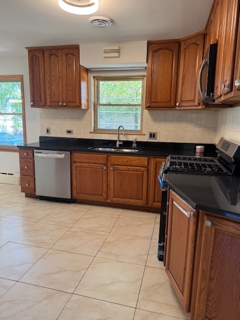 kitchen with appliances with stainless steel finishes, baseboard heating, sink, and tasteful backsplash