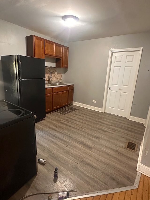 kitchen featuring backsplash, black appliances, dark hardwood / wood-style flooring, and sink