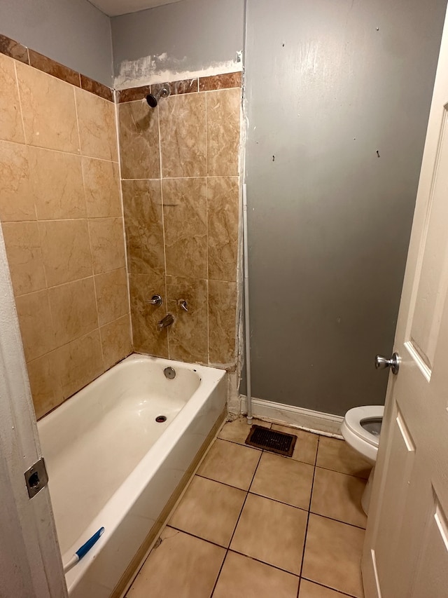 bathroom featuring tile patterned flooring, toilet, and tiled shower / bath combo