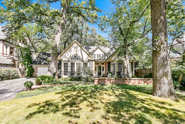 tudor-style house featuring a front yard and a garage