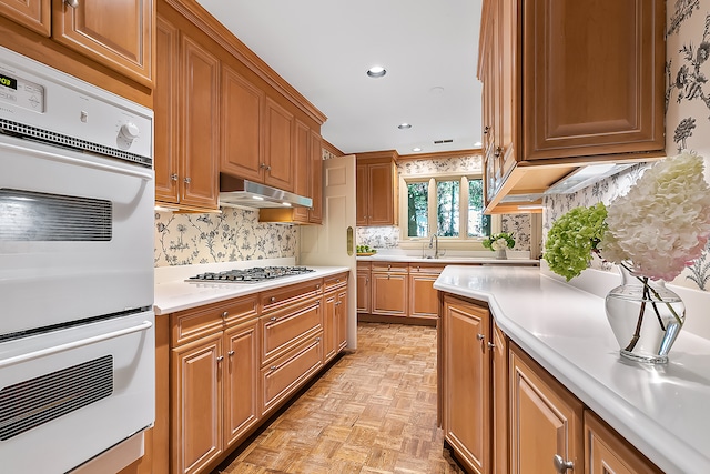 kitchen featuring stainless steel gas cooktop, tasteful backsplash, ventilation hood, light parquet floors, and white double oven