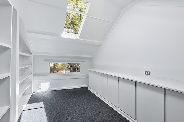 interior space with dark colored carpet and lofted ceiling with skylight