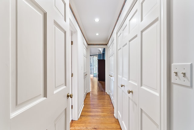 corridor featuring light wood-type flooring and crown molding