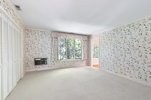 unfurnished living room featuring an AC wall unit, light colored carpet, and crown molding