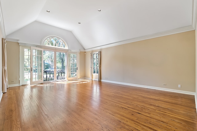 unfurnished living room with lofted ceiling, crown molding, a wealth of natural light, and light hardwood / wood-style flooring