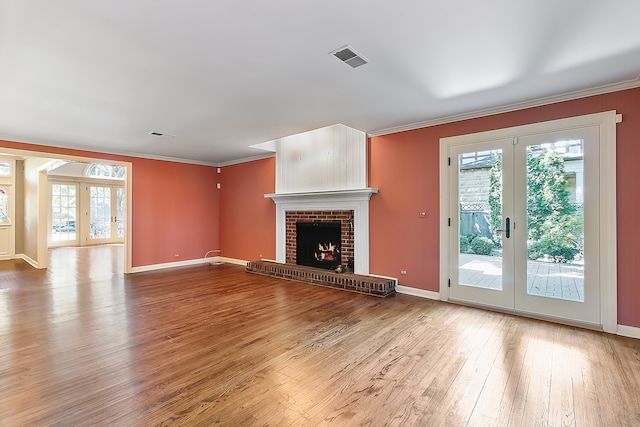 unfurnished living room featuring french doors, hardwood / wood-style flooring, a fireplace, and plenty of natural light