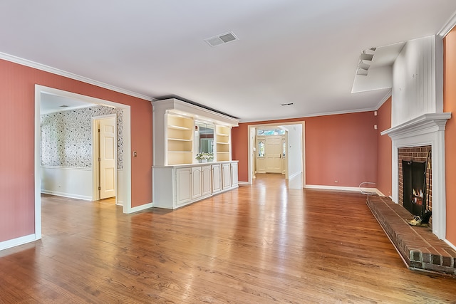 unfurnished living room featuring a brick fireplace, ornamental molding, and light hardwood / wood-style flooring