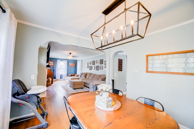 dining area with ceiling fan with notable chandelier, ornamental molding, and wood-type flooring