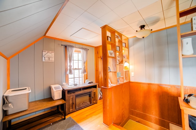 bathroom featuring hardwood / wood-style flooring, wooden walls, toilet, and vaulted ceiling