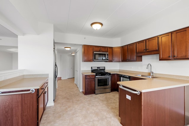 kitchen with light countertops, brown cabinets, appliances with stainless steel finishes, a peninsula, and a sink