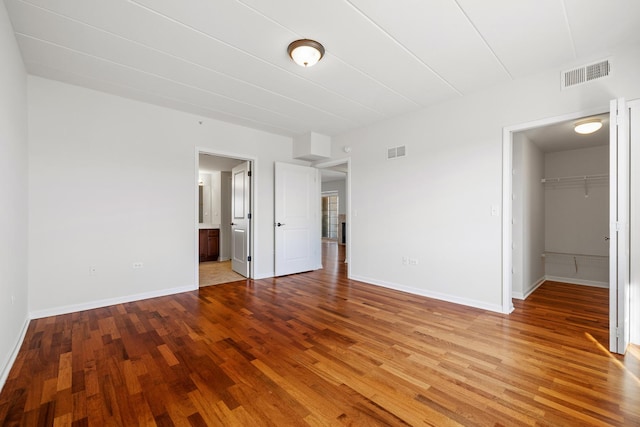 unfurnished room featuring wood finished floors, visible vents, and baseboards