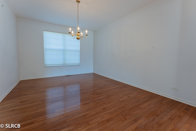 unfurnished room with wood-type flooring and a notable chandelier