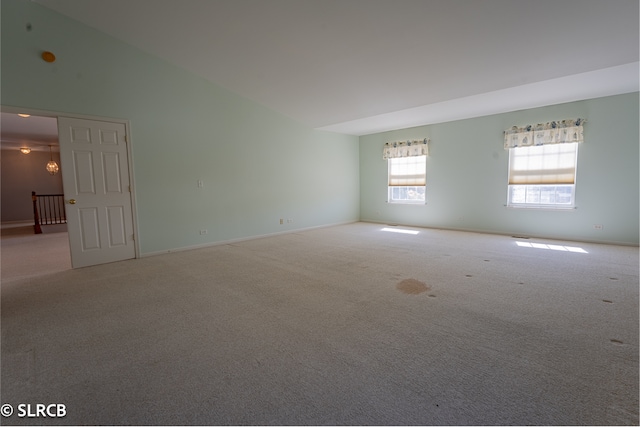 carpeted spare room with lofted ceiling