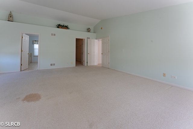 carpeted spare room with vaulted ceiling