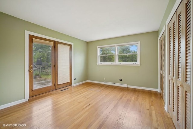 1087 Cedar Ln, Northbrook, IL 60062 - unfurnished bedroom featuring a baseboard radiator, multiple windows, light wood-type flooring, and baseboards